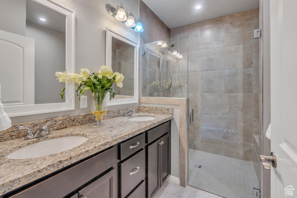 Bathroom with walk in shower, tile floors, dual sinks, and vanity with extensive cabinet space