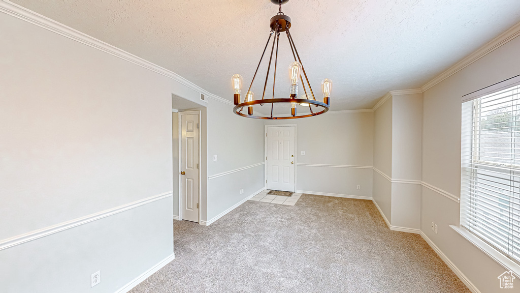 Carpeted empty room with an inviting chandelier, a textured ceiling, and crown molding