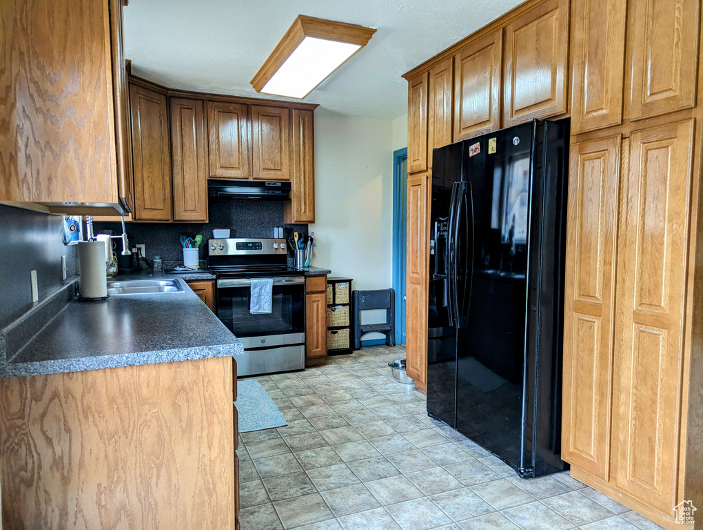 Kitchen with sink, light tile floors, stainless steel range with electric stovetop, black fridge with ice dispenser, and ventilation hood