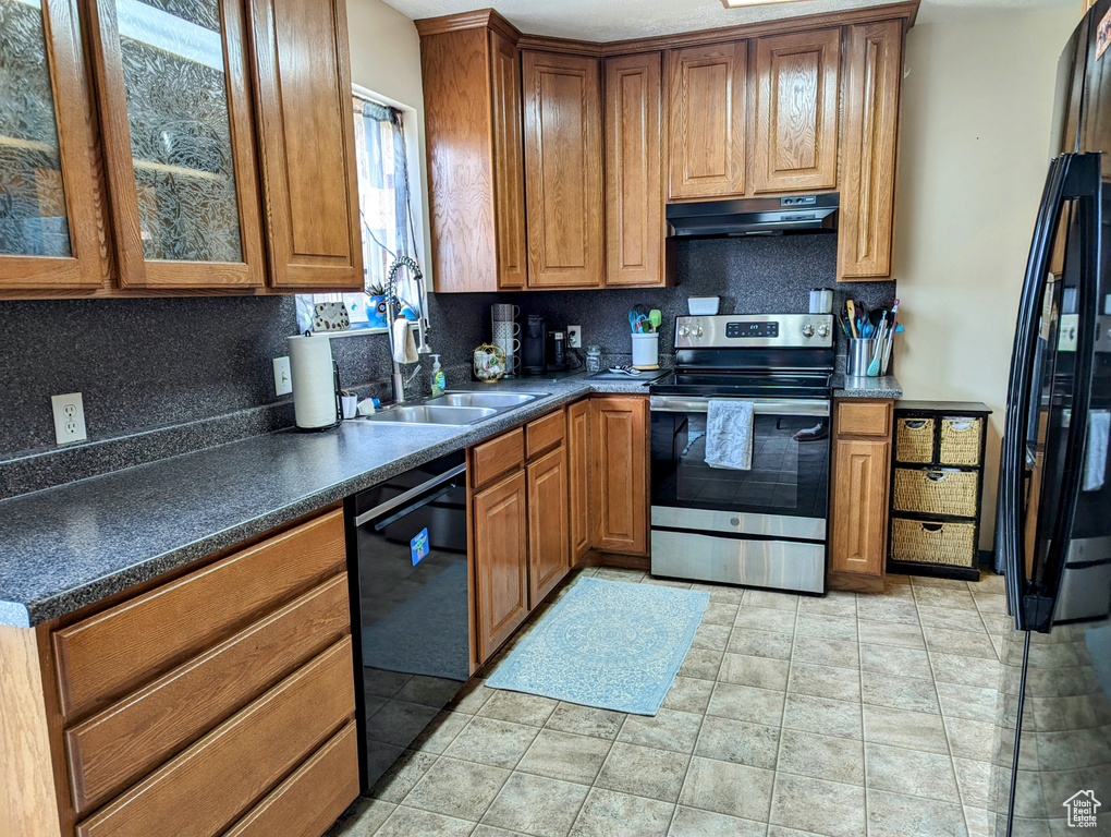 Kitchen with light tile floors, black dishwasher, stainless steel electric stove, tasteful backsplash, and sink
