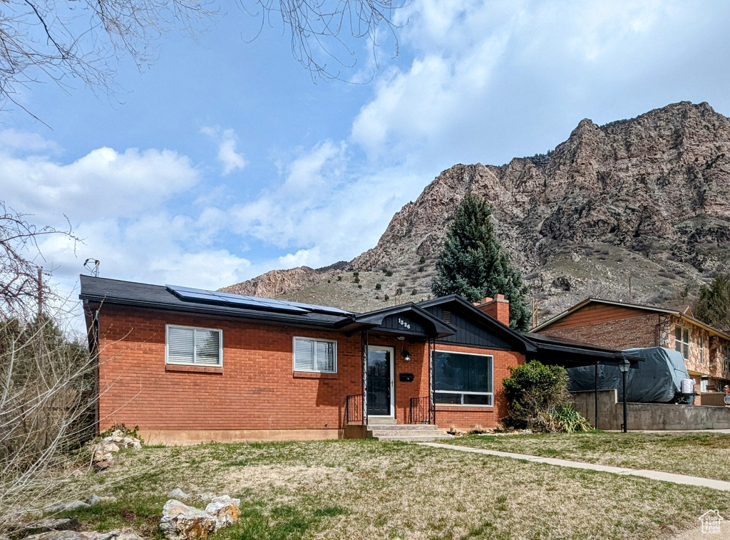 Back of property with a mountain view and a lawn