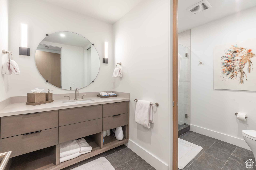 Bathroom featuring toilet, large vanity, tile floors, and walk in shower