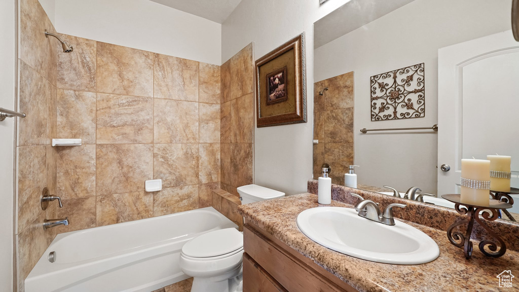 Full bathroom with tiled shower / bath combo, toilet, and vanity