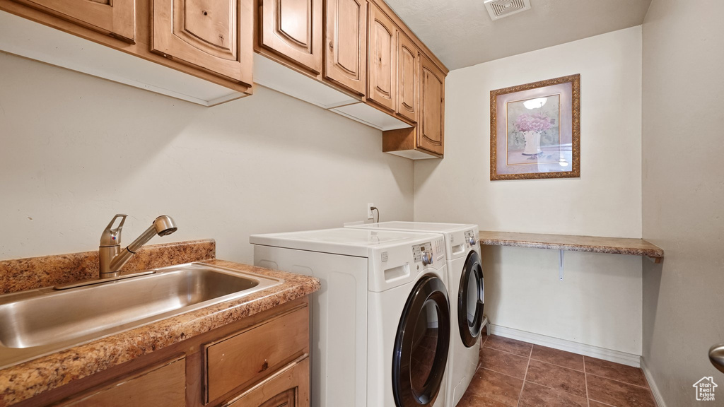 Laundry room with cabinets, dark tile floors, washer and dryer, and sink