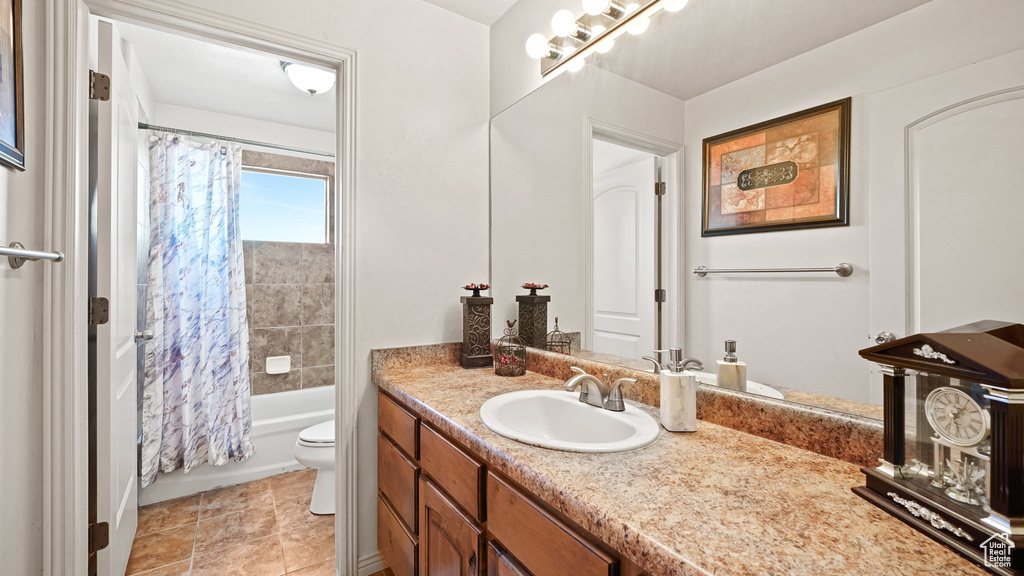 Full bathroom with toilet, shower / tub combo with curtain, vanity with extensive cabinet space, and tile flooring