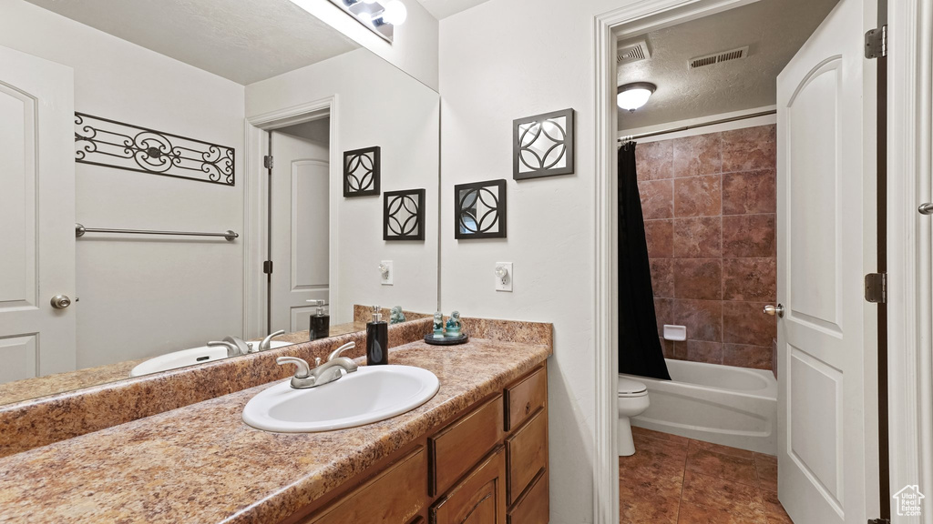 Full bathroom featuring toilet, shower / tub combo, tile flooring, oversized vanity, and a textured ceiling