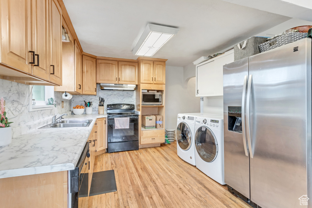 Kitchen with washing machine and dryer, light hardwood / wood-style floors, black appliances, and light brown cabinetry