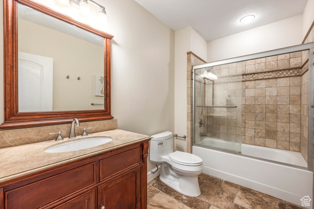 Full bathroom featuring toilet, combined bath / shower with glass door, large vanity, and tile floors