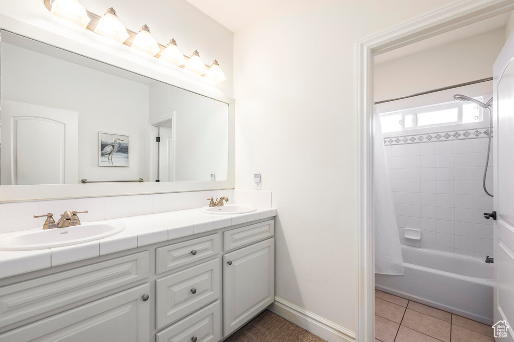 Bathroom with tile floors, large vanity, dual sinks, and shower / bathtub combination with curtain