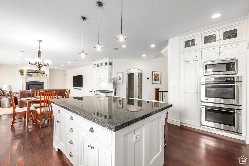 Kitchen featuring white cabinetry, dark hardwood / wood-style floors, stainless steel appliances, a center island, and pendant lighting
