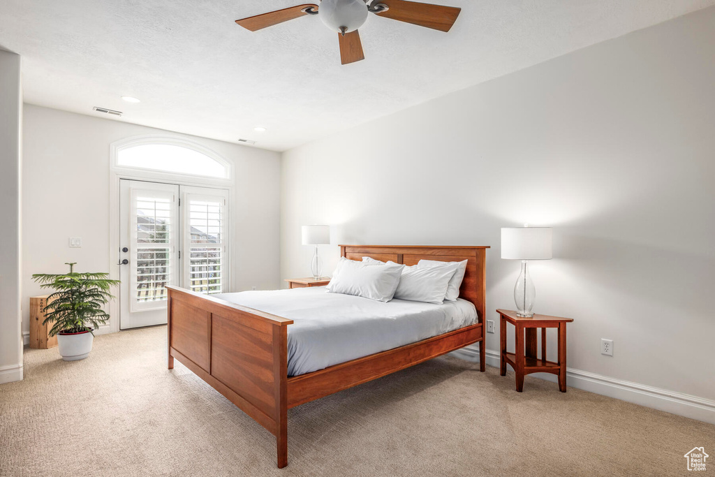 Bedroom with light colored carpet, ceiling fan, and access to outside