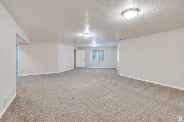 Basement featuring light carpet and a textured ceiling
