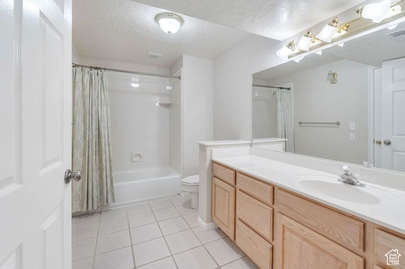 Full bathroom with vanity, shower / bath combo, tile floors, a textured ceiling, and toilet