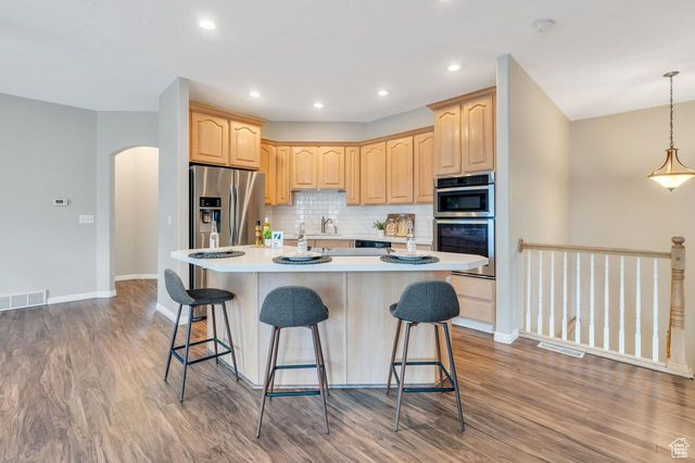 Kitchen featuring stainless steel appliances, decorative light fixtures, dark hardwood / wood-style flooring, and a center island