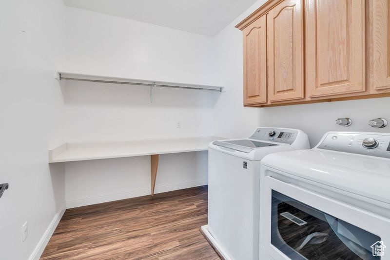 Laundry room featuring washer and dryer, cabinets, and dark hardwood / wood-style flooring