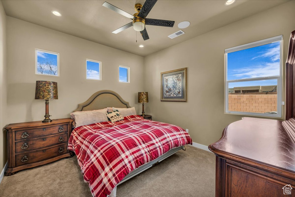 Bedroom with light colored carpet, multiple windows, and ceiling fan