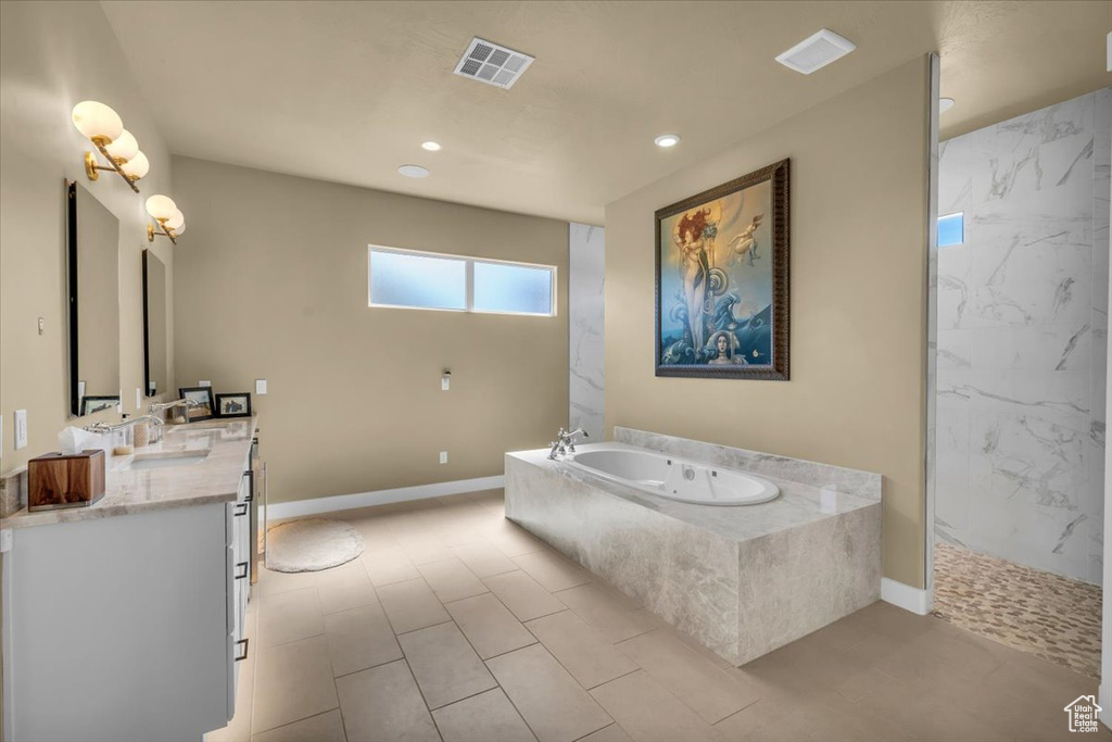 Bathroom with tile floors, dual sinks, vanity with extensive cabinet space, and independent shower and bath