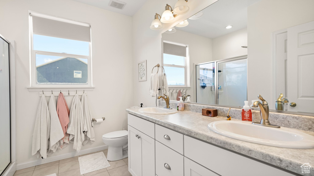 Bathroom featuring dual sinks, a healthy amount of sunlight, toilet, and vanity with extensive cabinet space