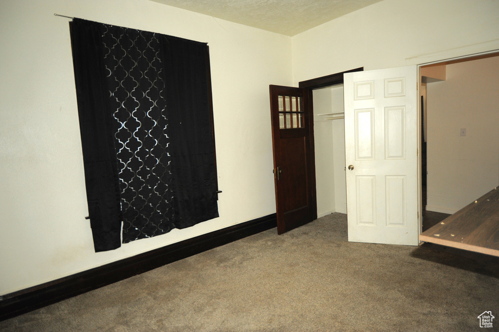 Interior space featuring dark colored carpet and a textured ceiling