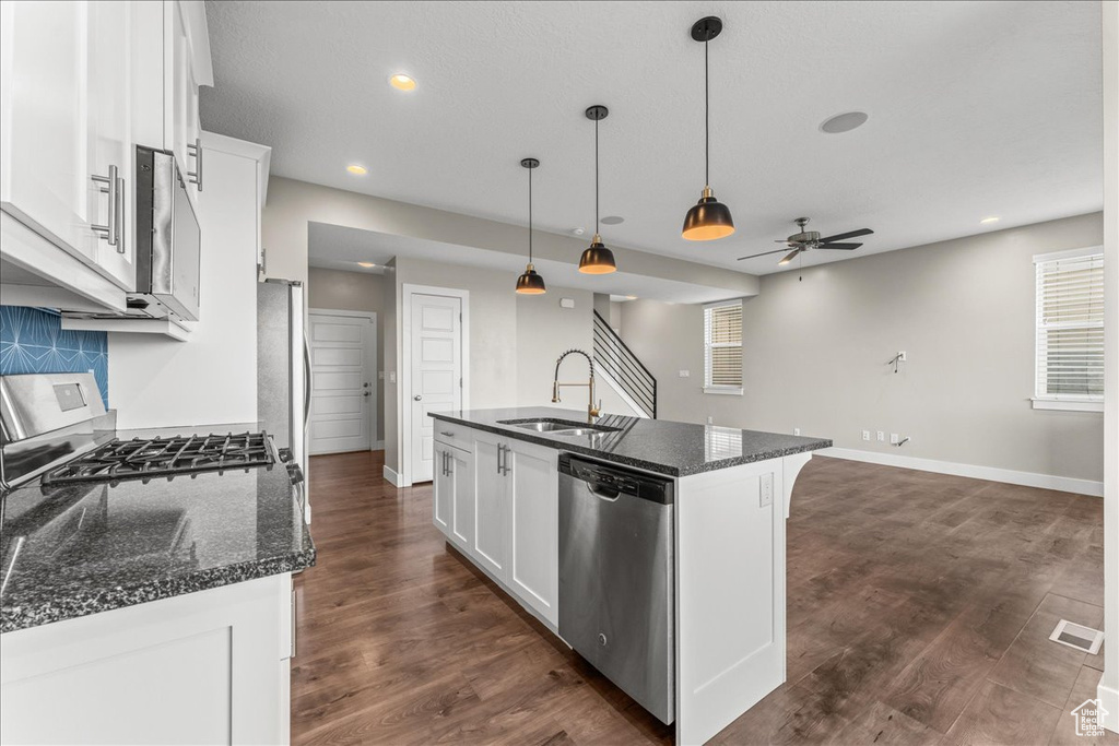 Kitchen with an island with sink, ceiling fan, hanging light fixtures, dark hardwood / wood-style flooring, and dishwasher