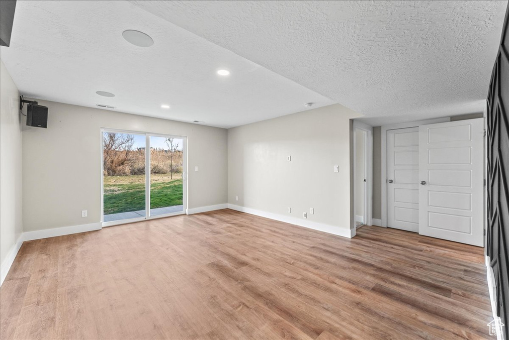 Empty room featuring a textured ceiling and light hardwood / wood-style floors