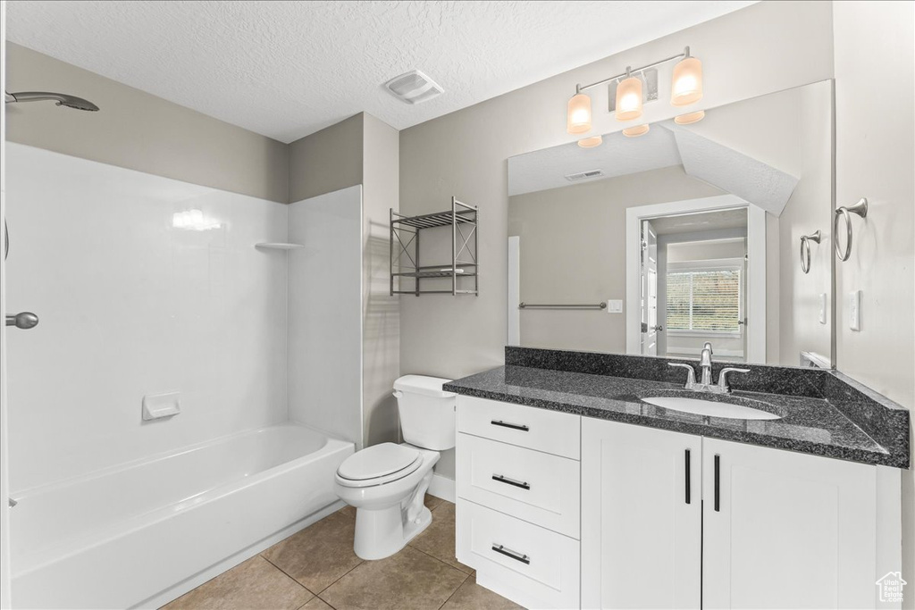 Full bathroom featuring vanity, tile floors, tub / shower combination, a textured ceiling, and toilet