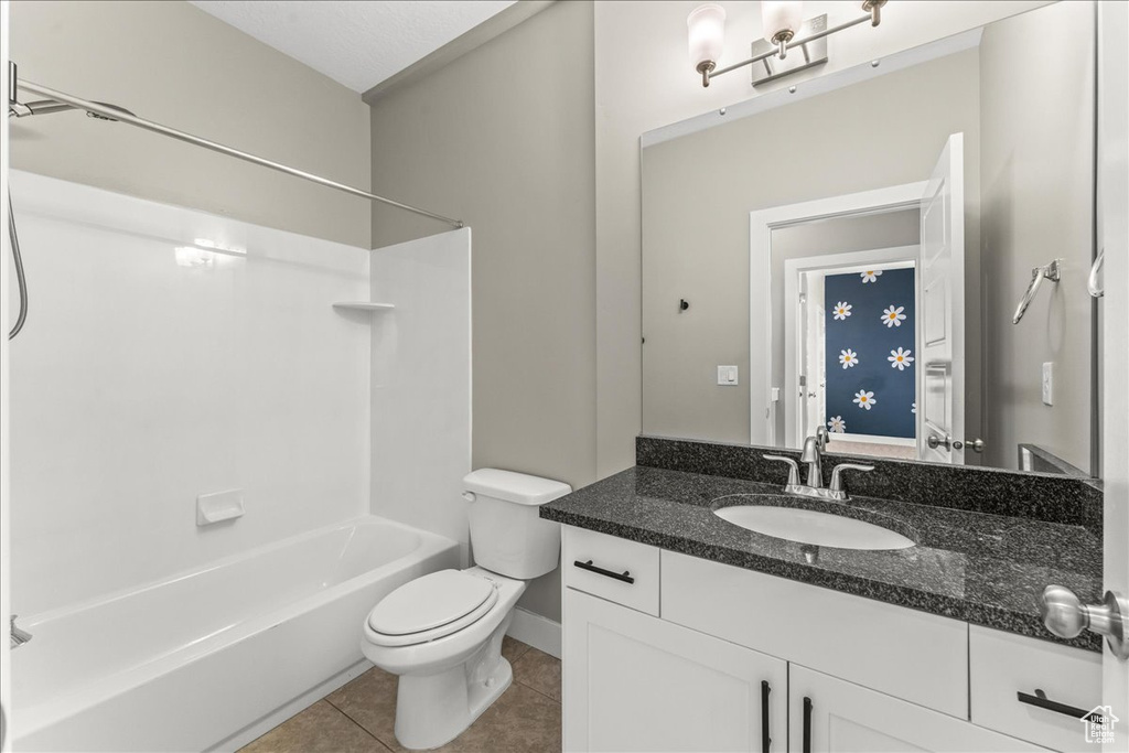 Full bathroom with  shower combination, toilet, vanity with extensive cabinet space, and tile flooring