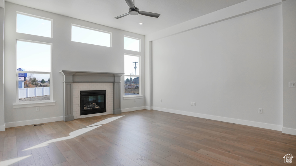 Unfurnished living room featuring a fireplace, ceiling fan, and light hardwood / wood-style flooring
