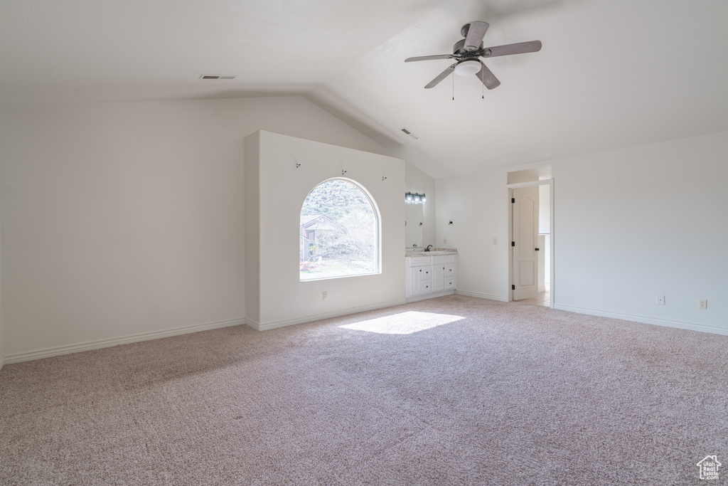 Interior space featuring light carpet, ceiling fan, and vaulted ceiling