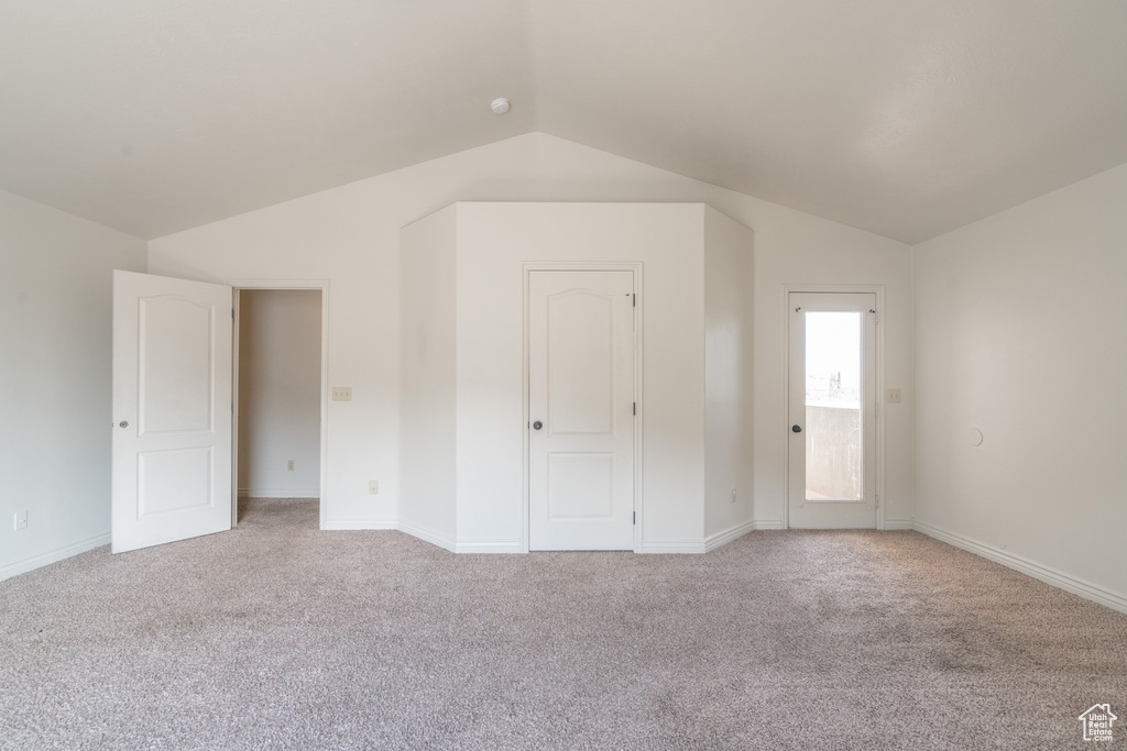 Unfurnished bedroom featuring lofted ceiling and light colored carpet