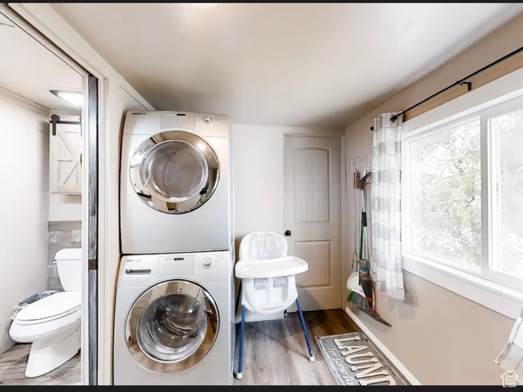 Laundry area with light wood-type flooring and stacked washer and clothes dryer