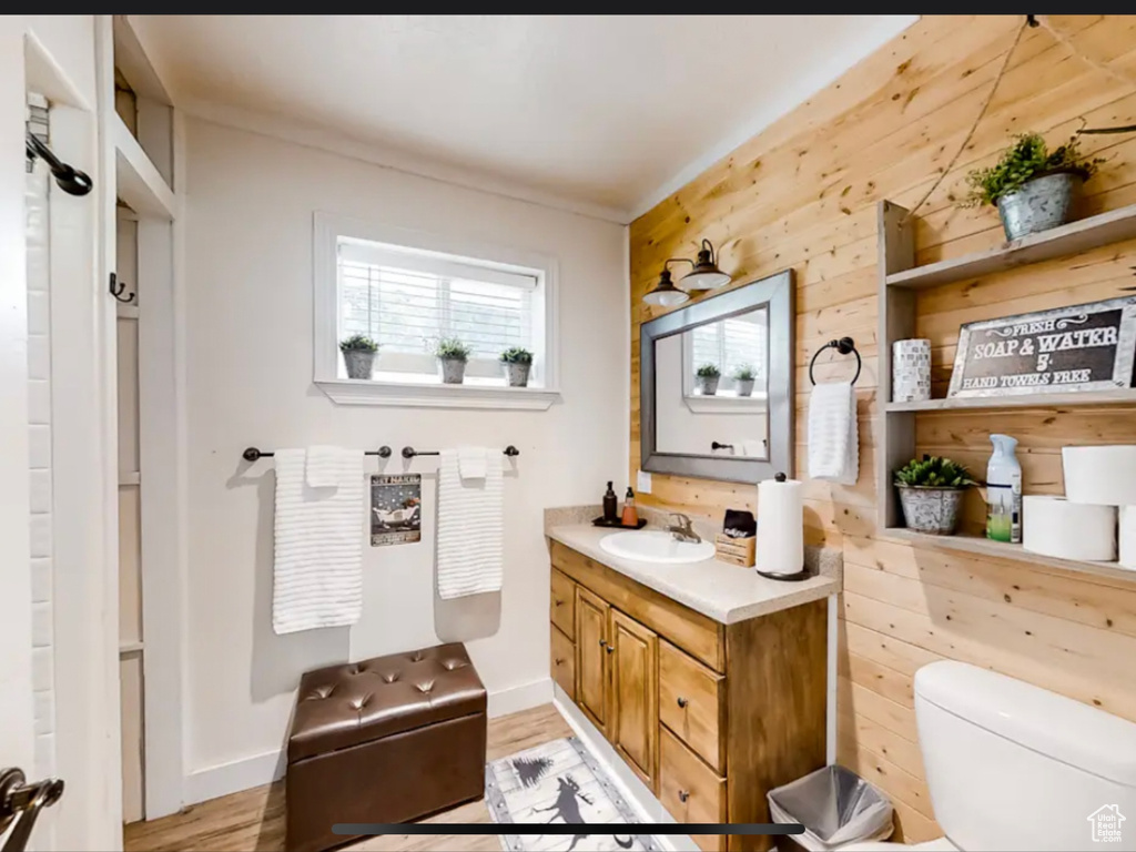 Bathroom featuring hardwood / wood-style flooring, vanity, wood walls, and toilet