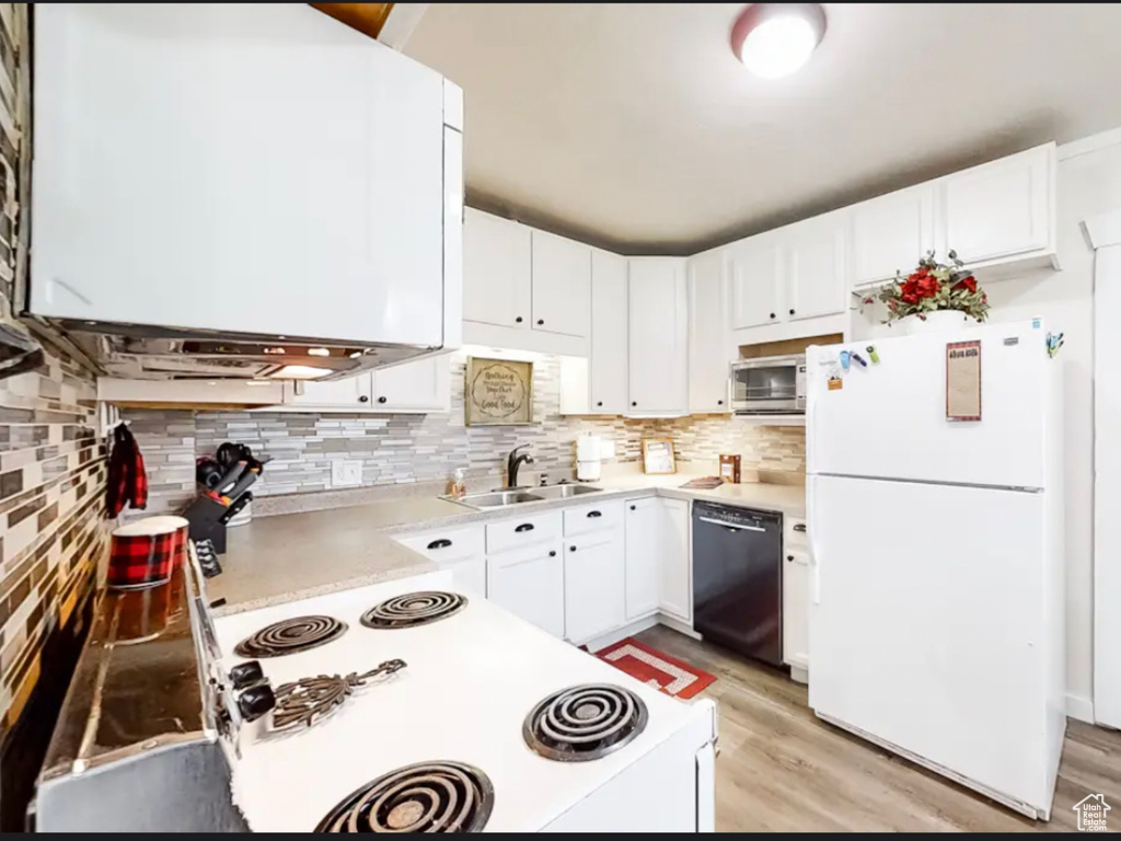 Kitchen featuring light hardwood / wood-style floors, white fridge, black dishwasher, white cabinetry, and sink