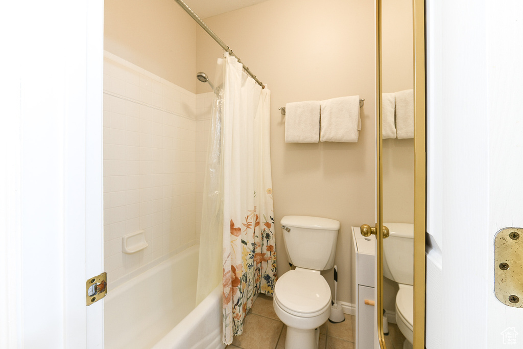 Bathroom with tile floors, shower / bath combo with shower curtain, and toilet