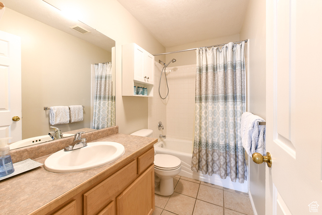 Full bathroom with tile floors, oversized vanity, toilet, and shower / bathtub combination with curtain