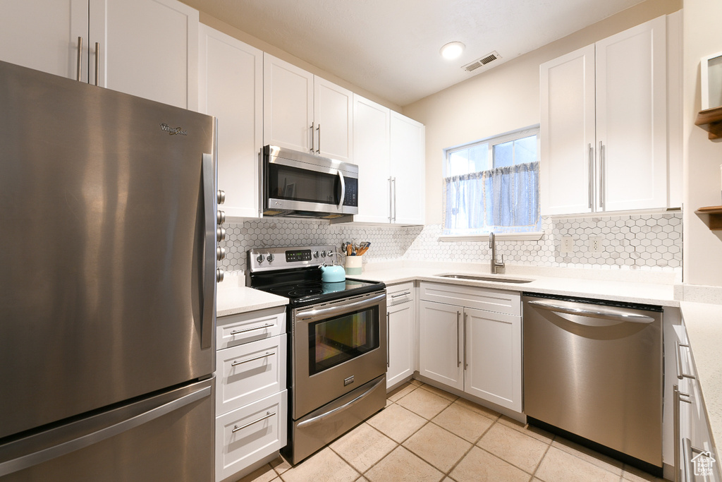 Kitchen with white cabinets, appliances with stainless steel finishes, and sink