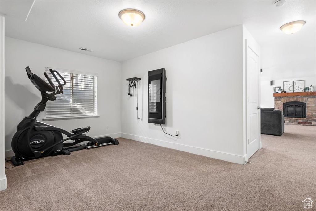 Workout area featuring light carpet and a stone fireplace