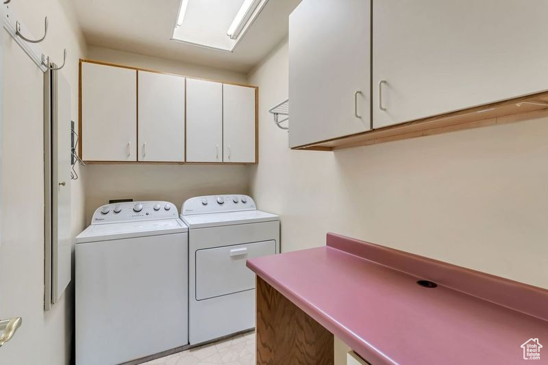 Laundry area with light tile floors, cabinets, and independent washer and dryer