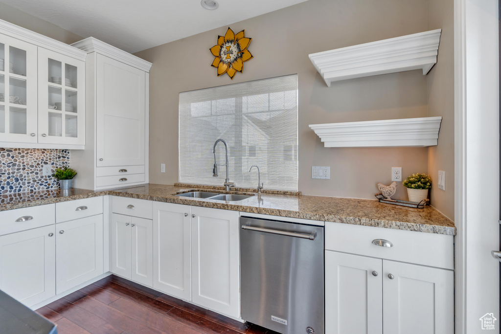 Kitchen with white cabinetry, backsplash, stainless steel dishwasher, and sink