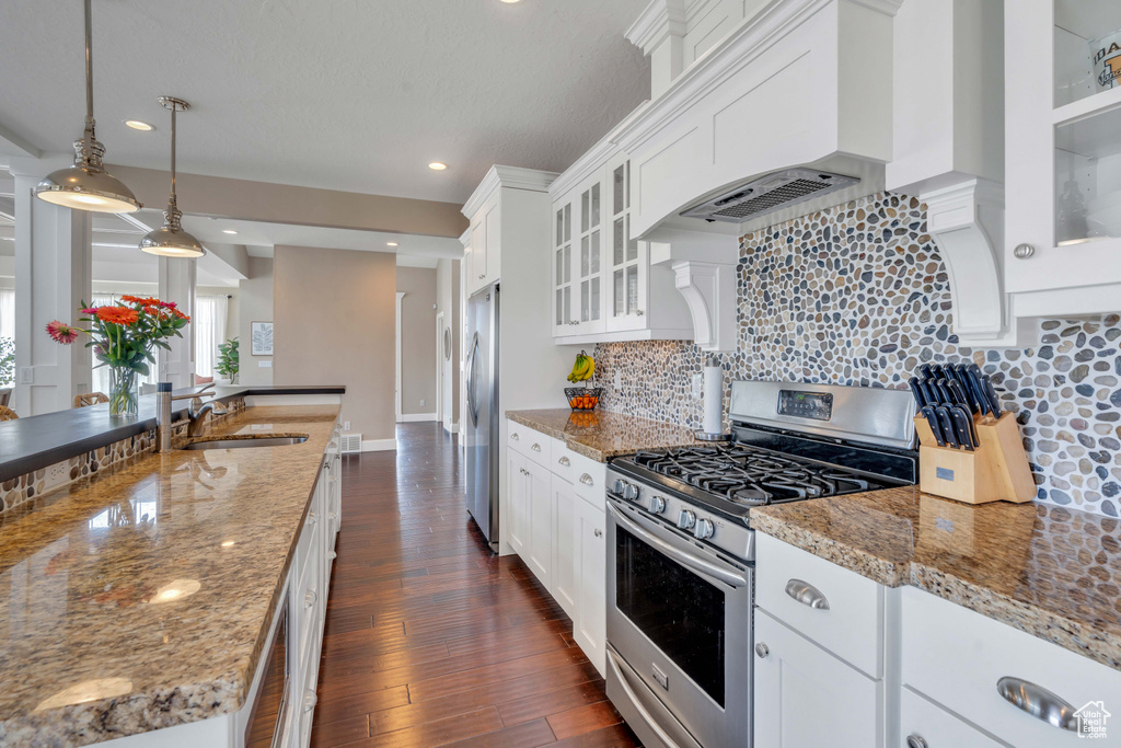 Kitchen with white cabinets, tasteful backsplash, appliances with stainless steel finishes, and light stone counters