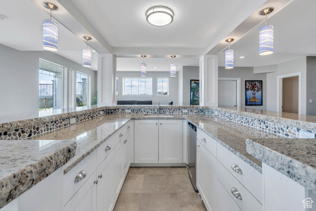 Kitchen with light tile floors, hanging light fixtures, and light stone countertops
