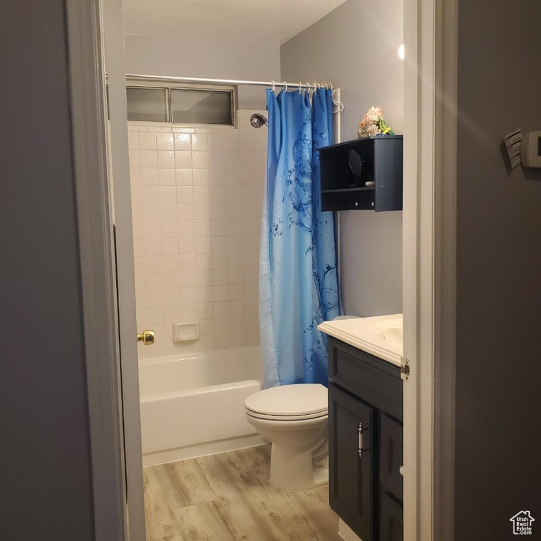 Full bathroom featuring toilet, shower / bath combo, hardwood / wood-style floors, and vanity