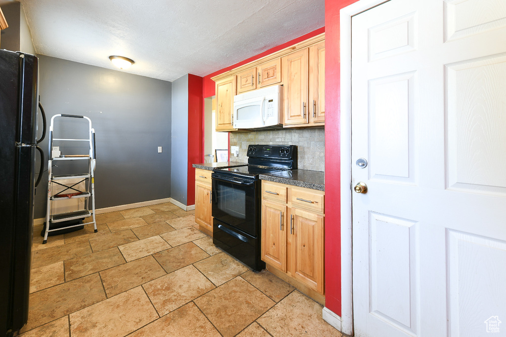 Kitchen featuring light tile floors, light brown cabinets, tasteful backsplash, and black appliances