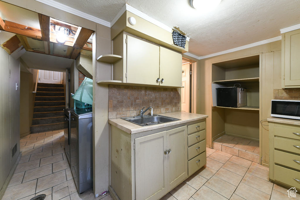 Kitchen with light tile floors, backsplash, sink, and ornamental molding