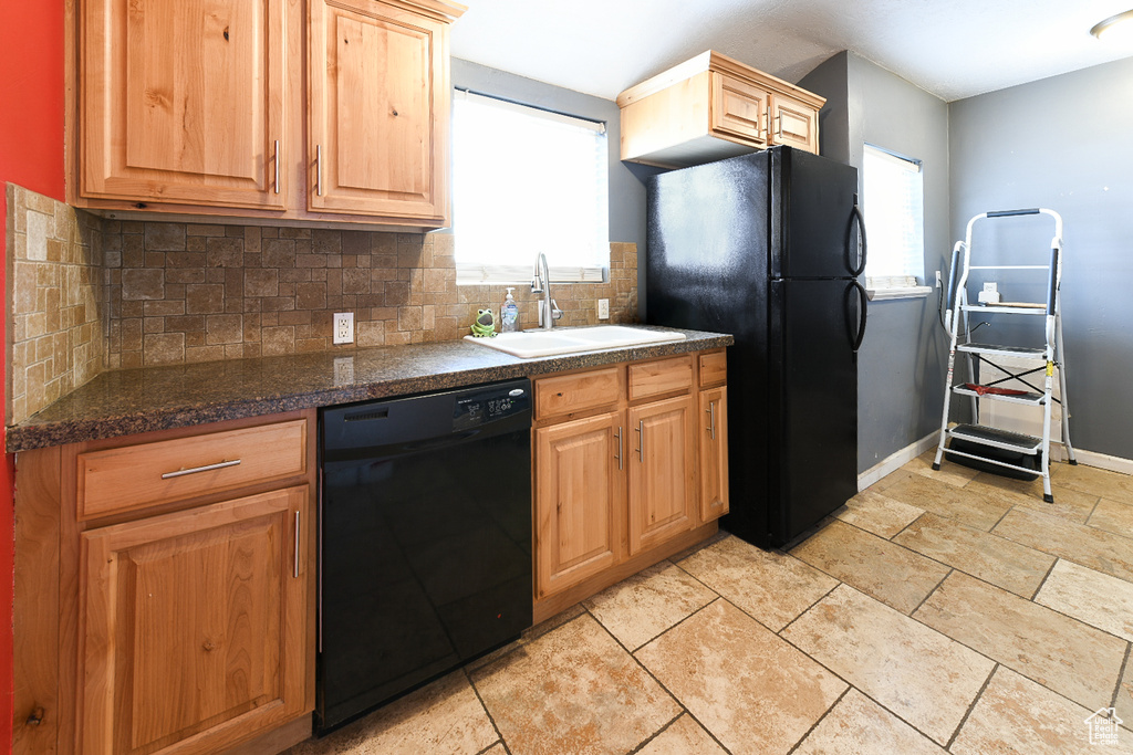 Kitchen with backsplash, a healthy amount of sunlight, black appliances, and sink