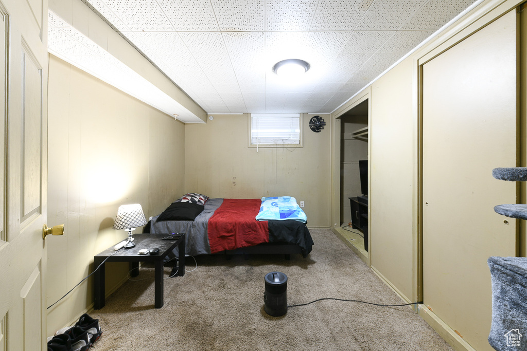 Bedroom with a paneled ceiling and light colored carpet