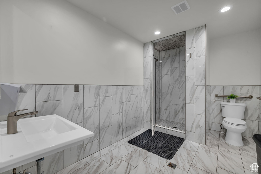 Bathroom featuring tile walls, toilet, a tile shower, and tile floors