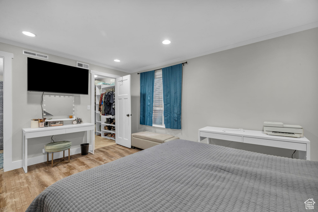 Bedroom with crown molding, light hardwood / wood-style floors, a spacious closet, and a closet