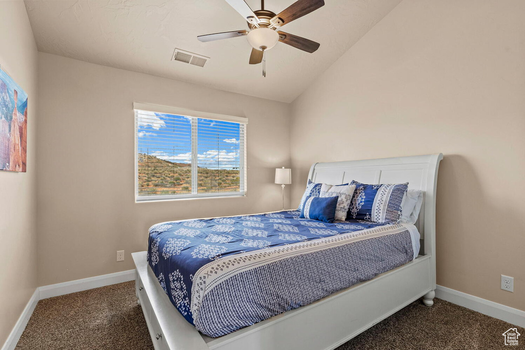Bedroom with ceiling fan, vaulted ceiling, and dark colored carpet