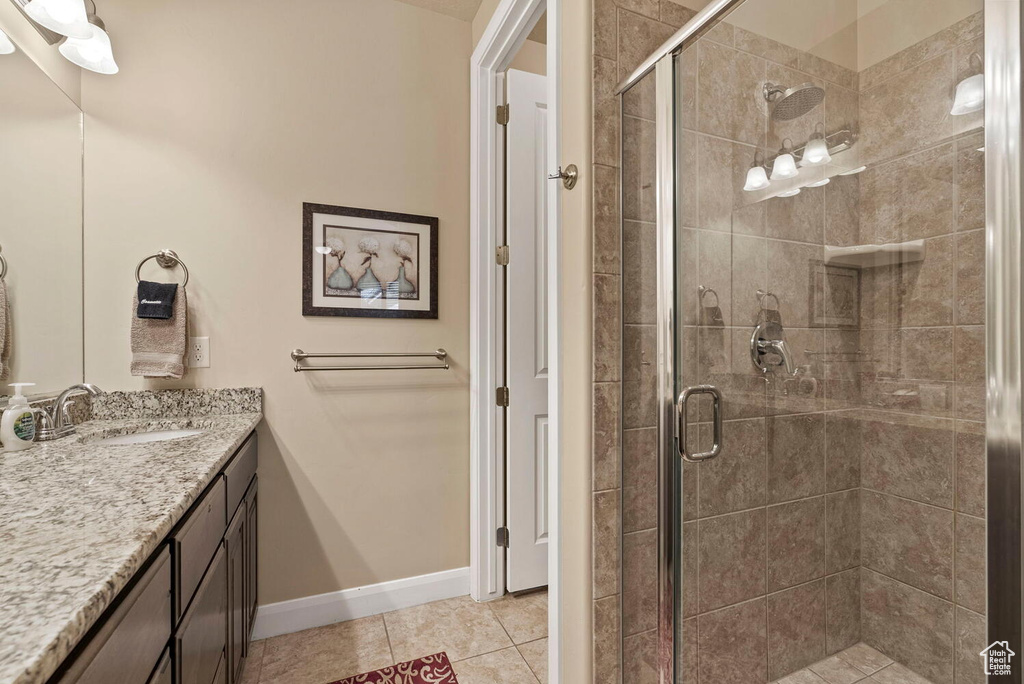 Bathroom featuring an enclosed shower, tile flooring, and vanity with extensive cabinet space